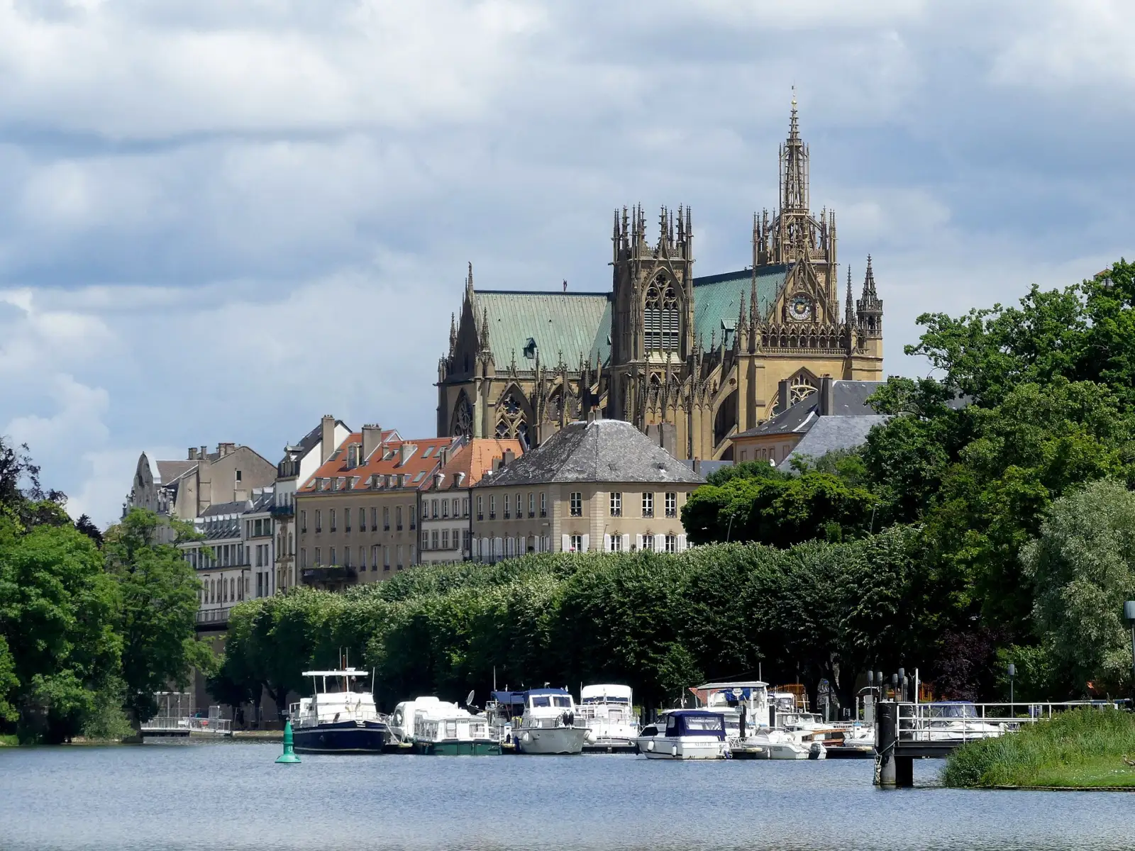 La Moselle à Metz, avec des bateaux amarrés au port du quai des Régates, des immeubles anciens et la cathédrale Saint-Étienne en arrière-plan