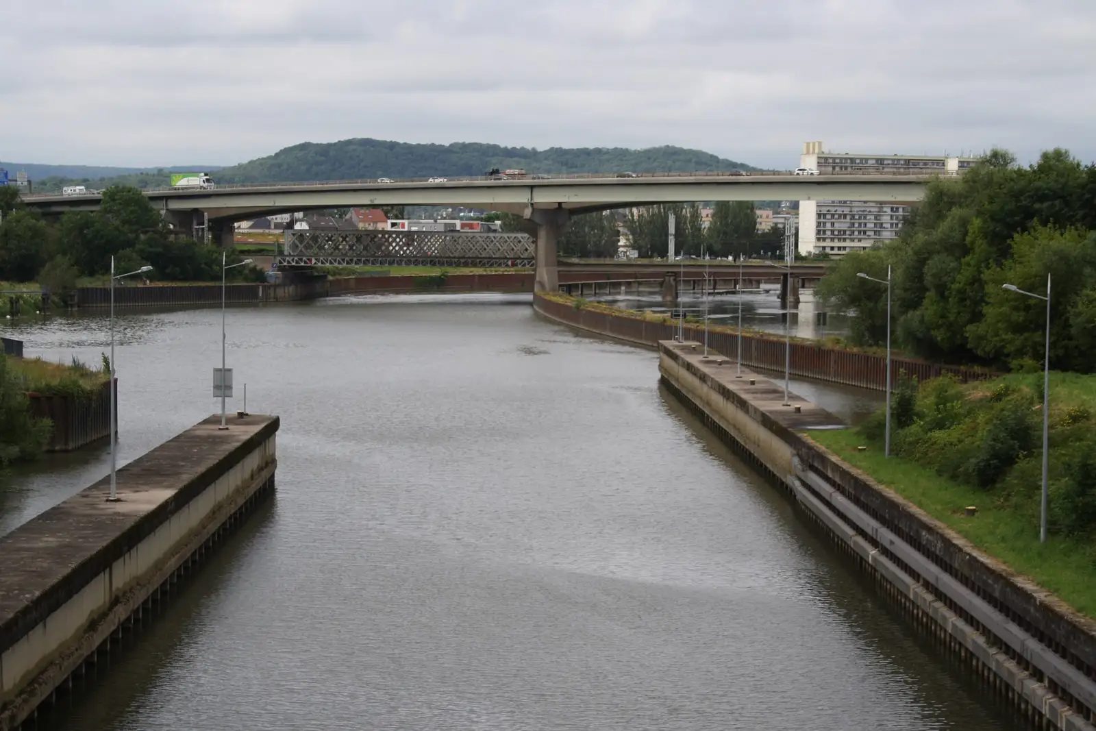 Le pont de l'autoroute A31 franchissant la Moselle à Thionville, avec des camions et des voitures sur le tablier, vu depuis une écluse