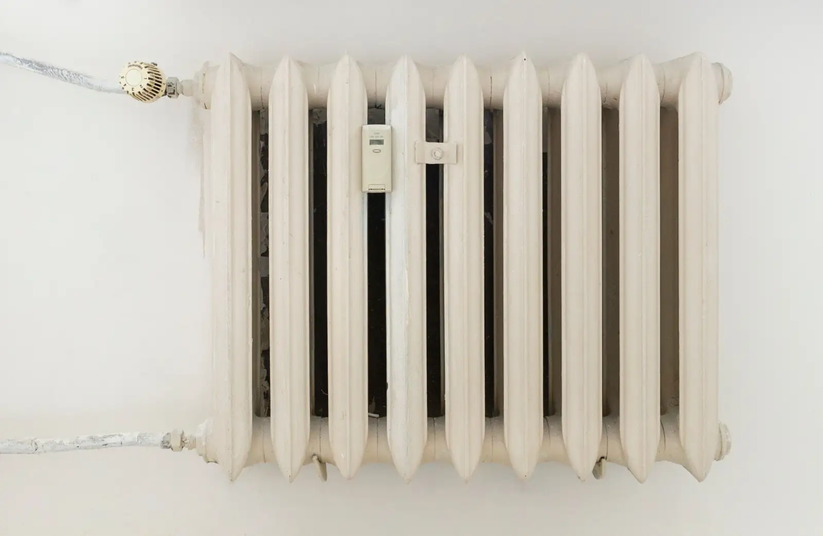 Radiateur en fonte ancien peint en blanc, avec robinet thermostatique et répartiteur de frais de chauffage