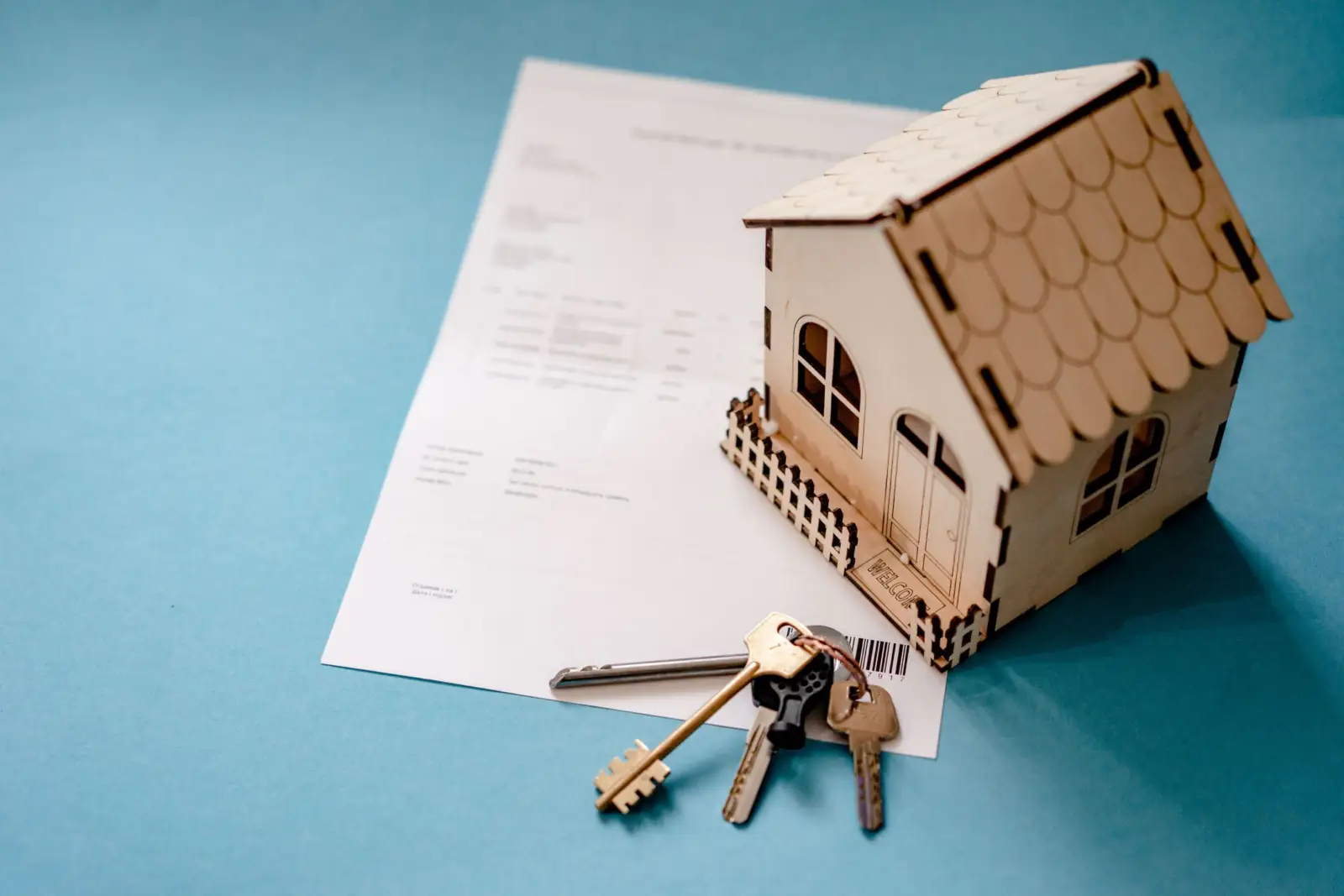 Maquette de maison en bois posée sur un contrat, avec un trousseau de clés