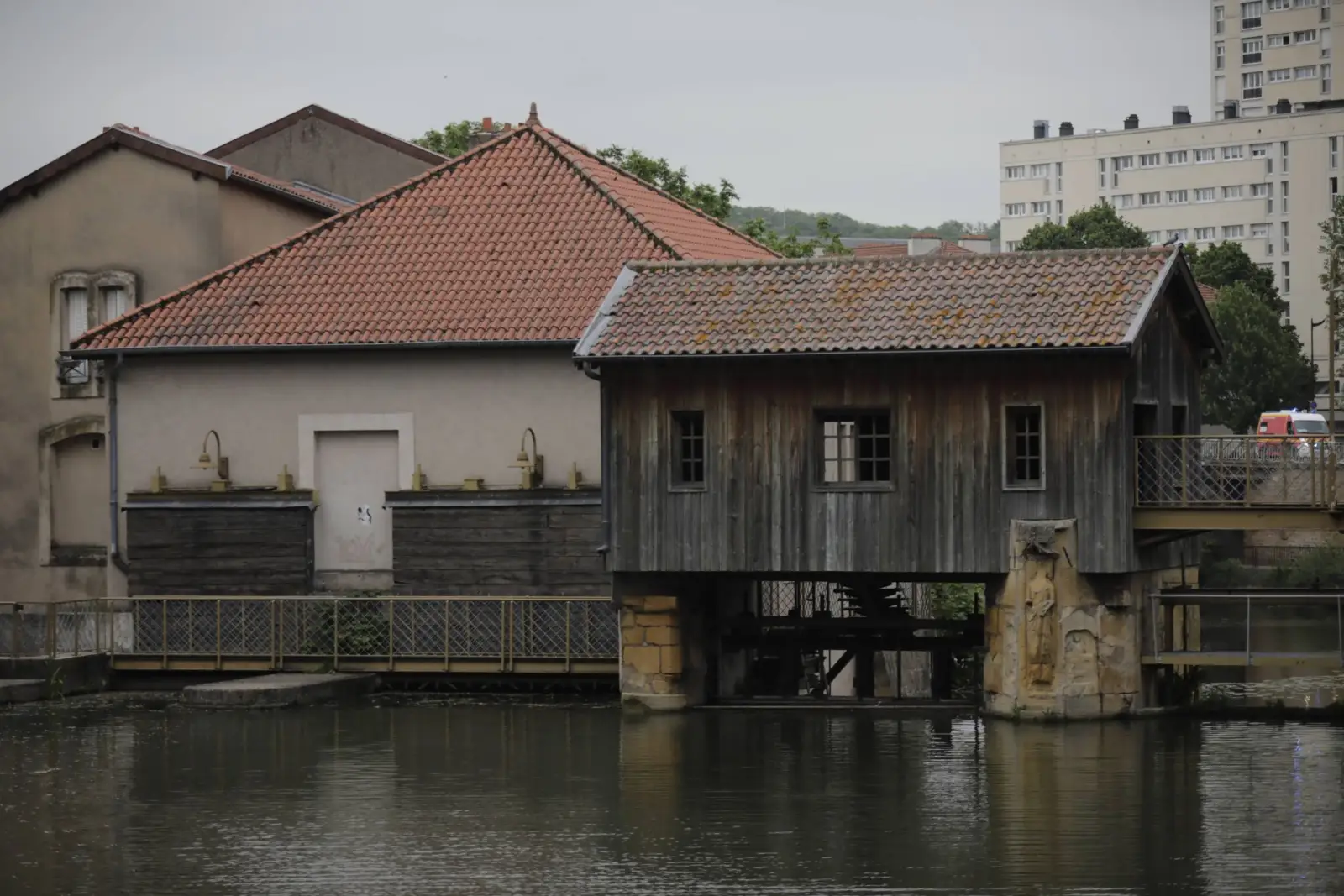 Anciens bâtiments au bord de l'eau à Metz, avec un immeuble d'habitation en arrière-plan