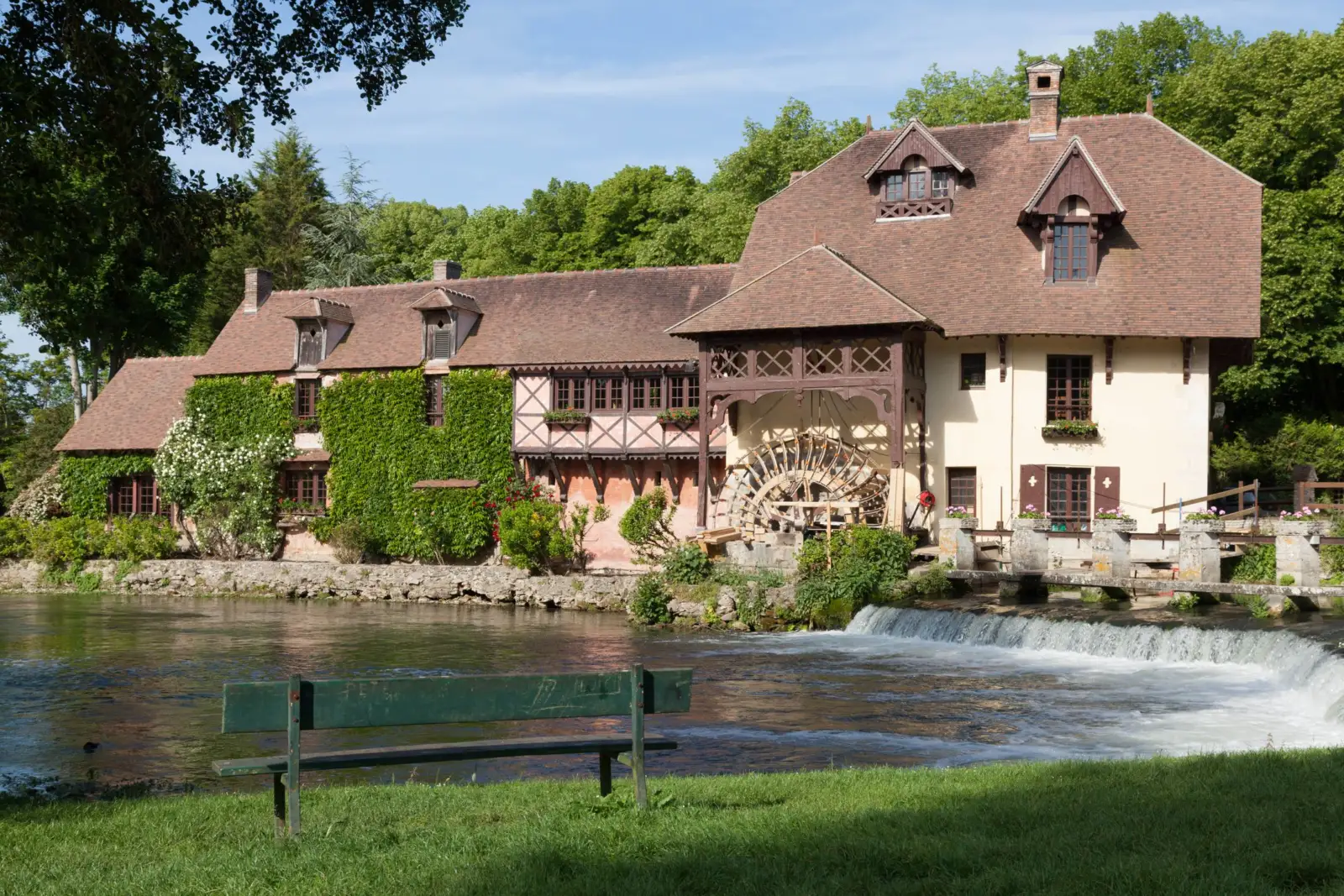 Ancien moulin à eau à colombages au bord d'une rivière, avec sa roue et un déversoir, à Gasny dans l'Eure