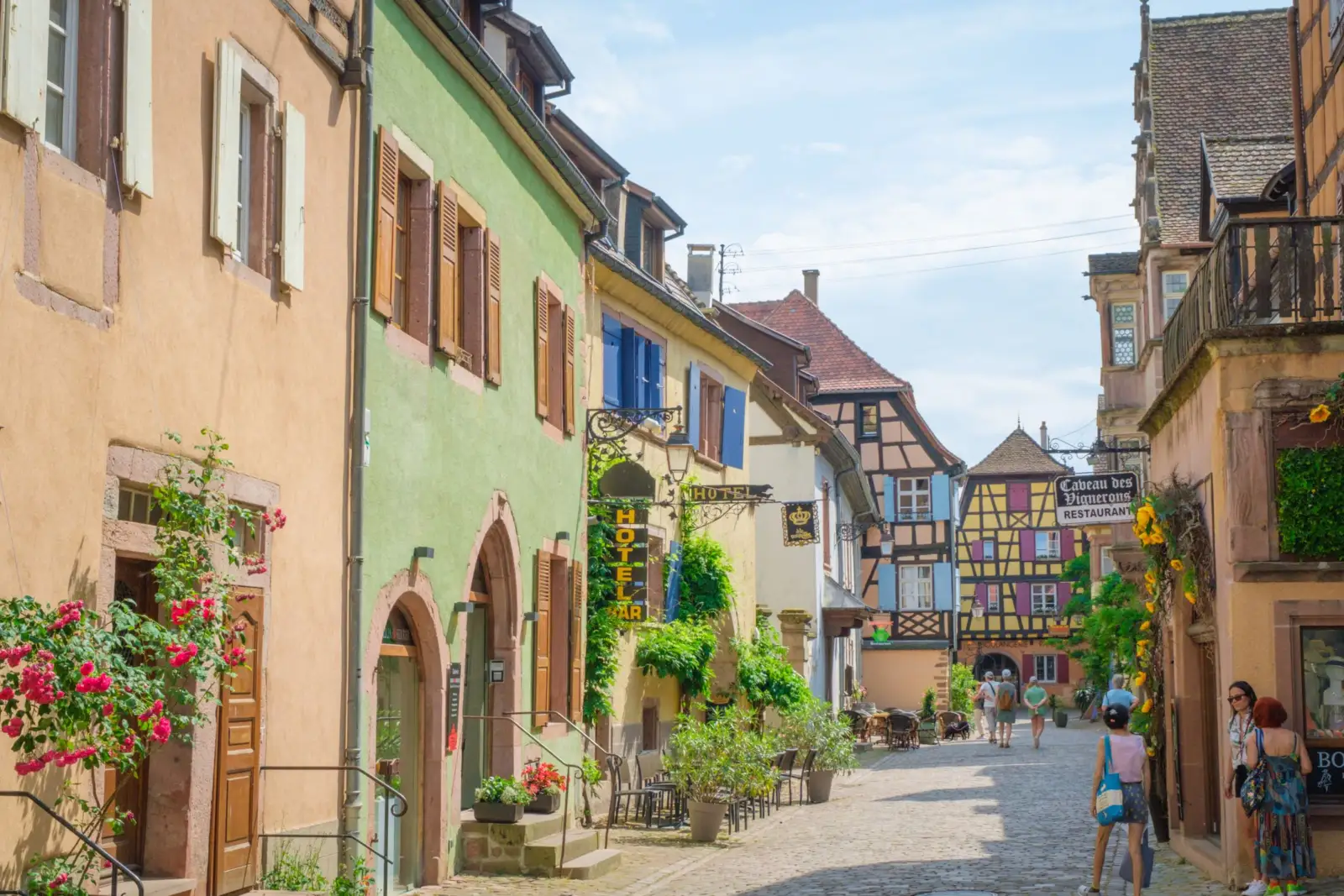 Rue pavée d'un village d'Alsace bordée de façades colorées et de maisons à colombages