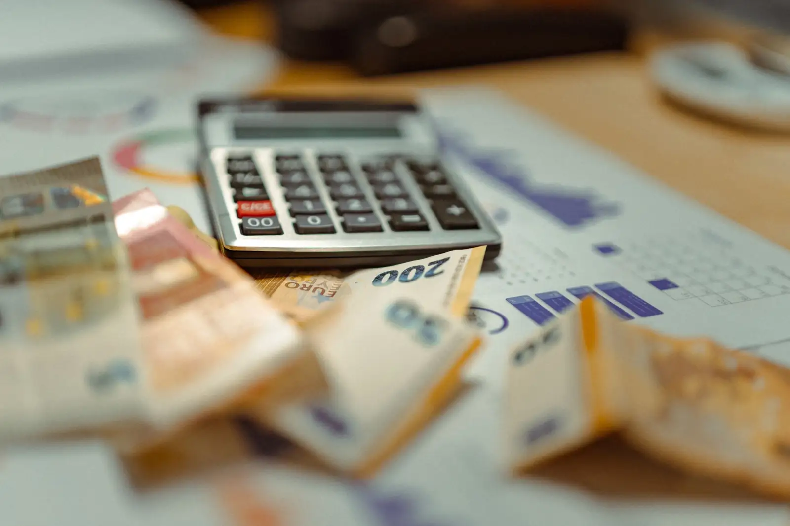 Billets en euros posés sur des documents financiers à côté d'une calculatrice