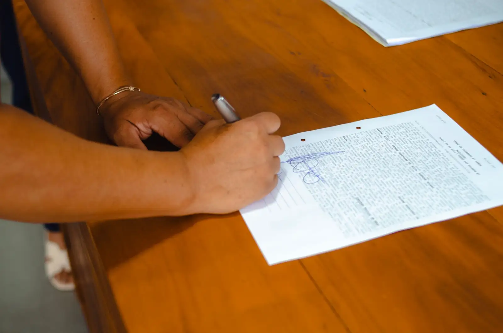 Mains signant un document juridique posé sur une table en bois