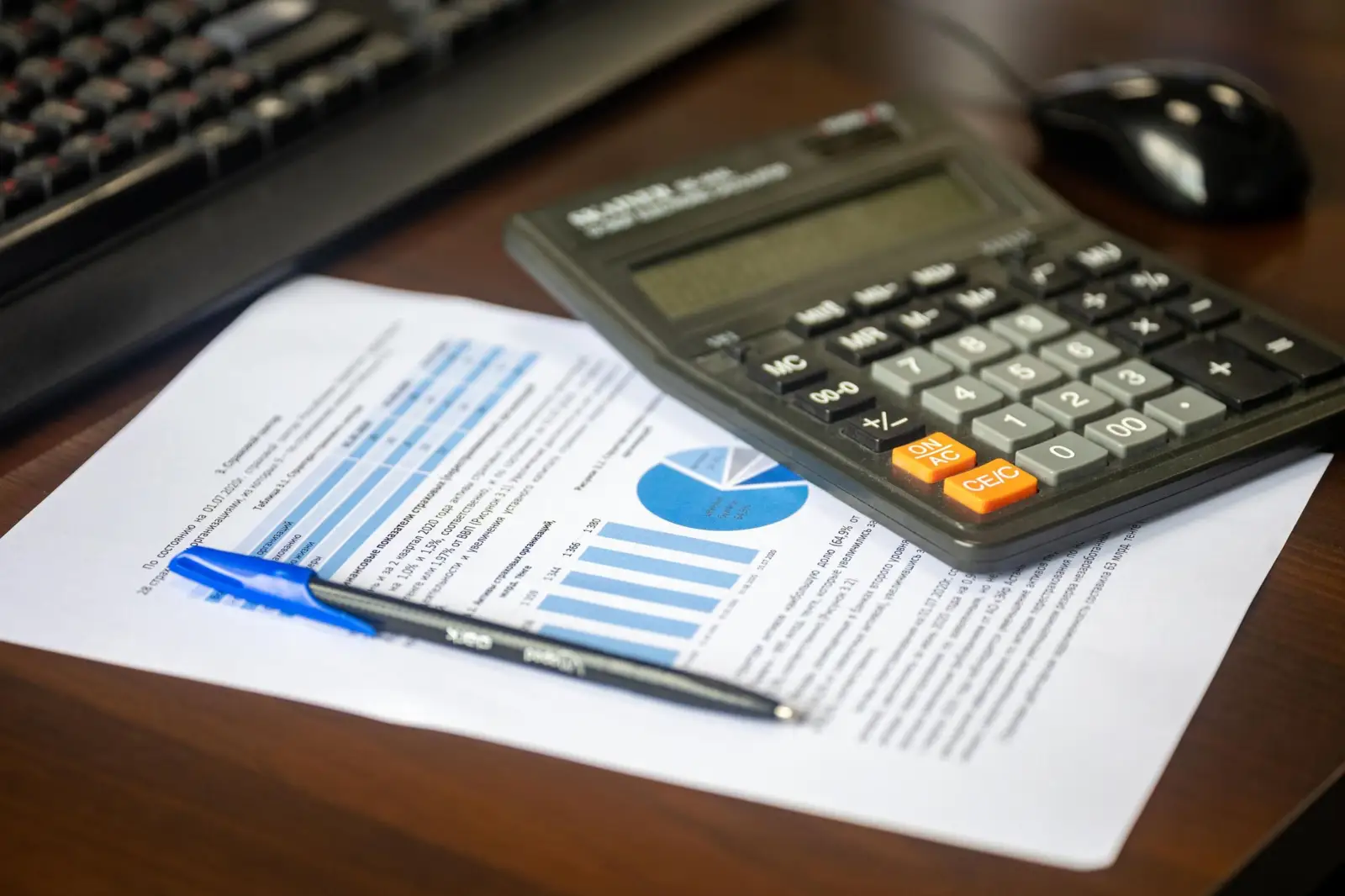Calculatrice, stylo et document financier avec graphiques posés sur un bureau