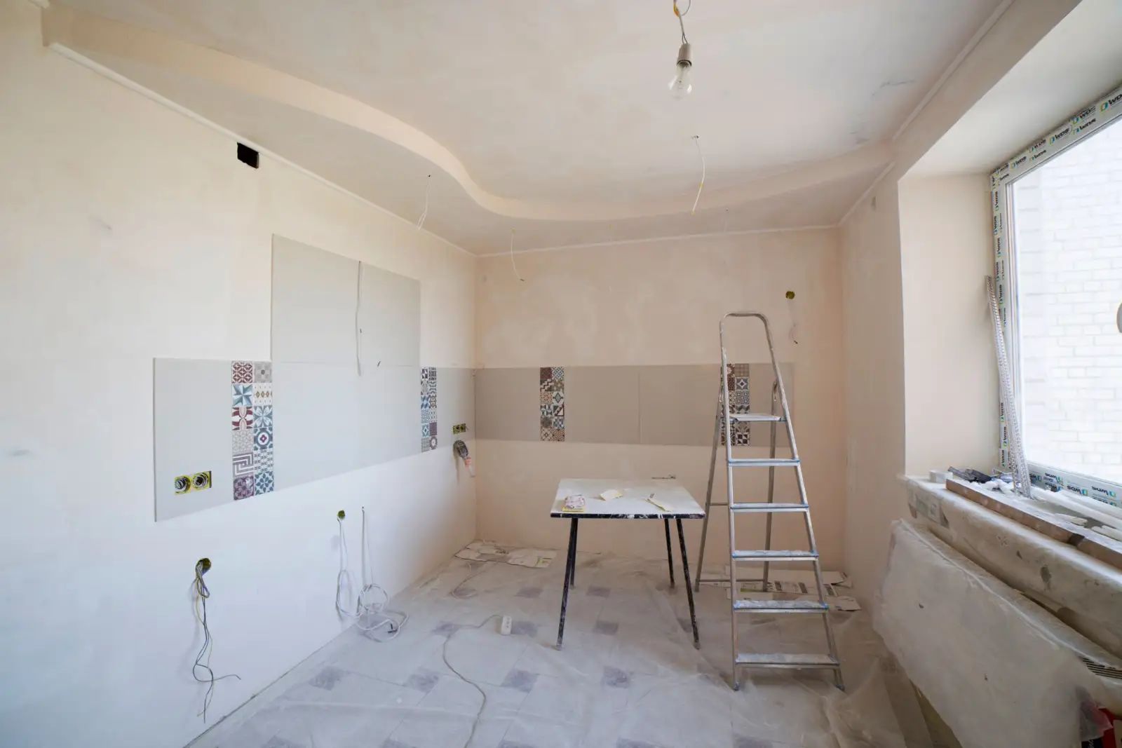 Pièce d'appartement en rénovation, murs enduits, escabeau et table de chantier