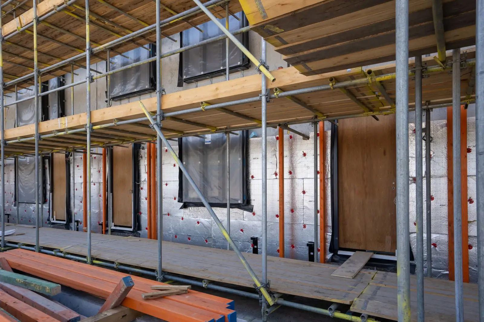 Façade d'immeuble sous échafaudage, panneaux isolants posés entre les fenêtres