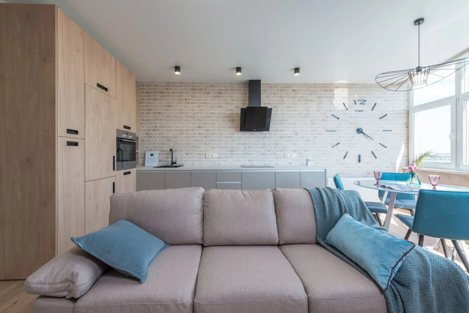 Studio meublé moderne avec canapé gris, table à manger et coin cuisine