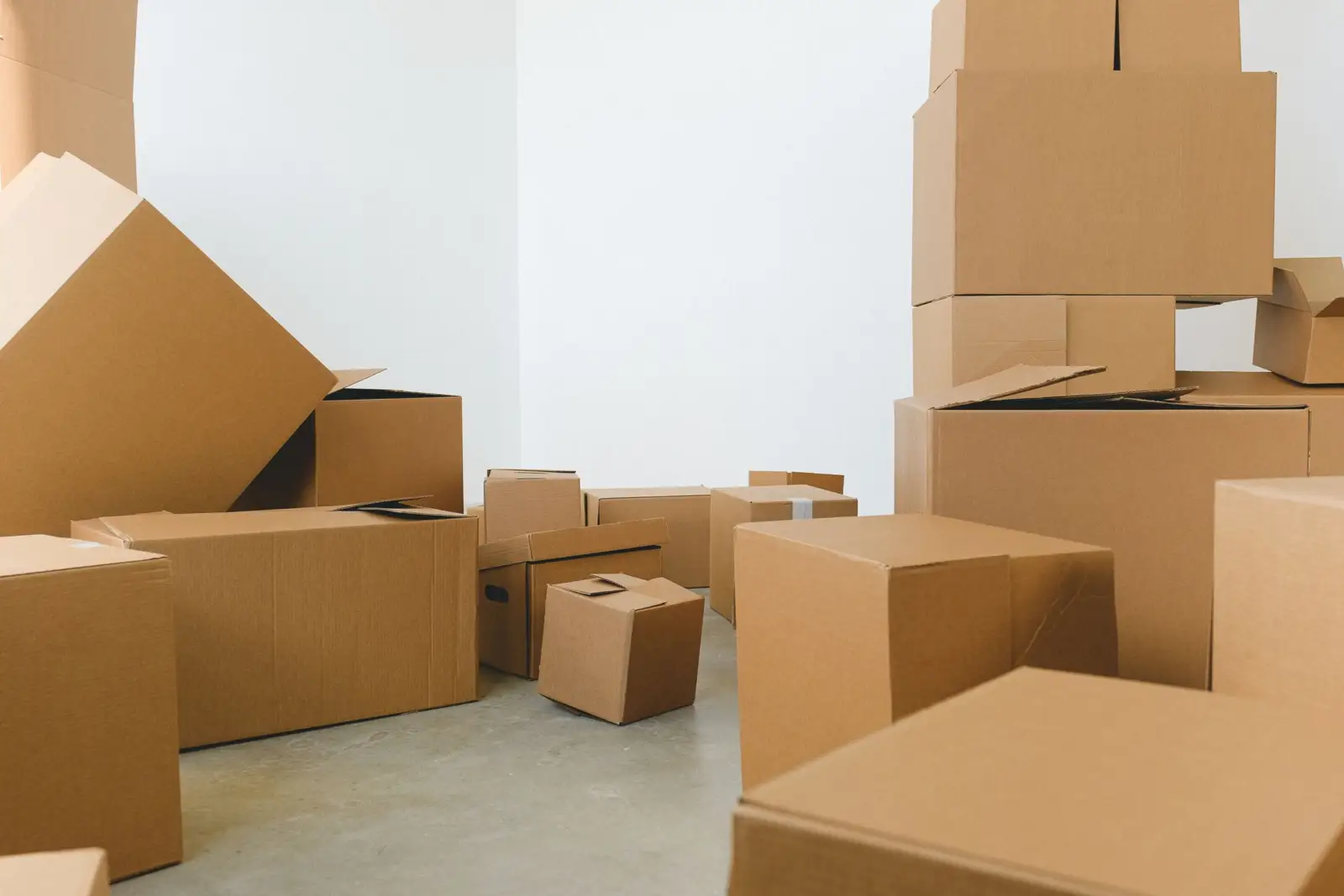 Cartons de déménagement empilés dans une pièce vide aux murs blancs