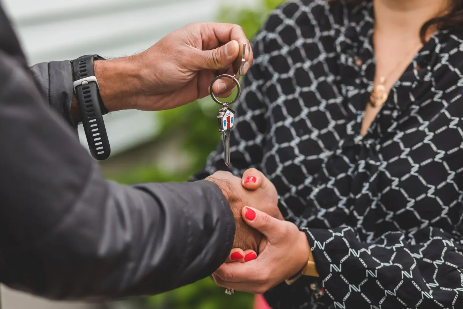 Poignée de main entre deux personnes, l'une tenant de son autre main une clé de maison